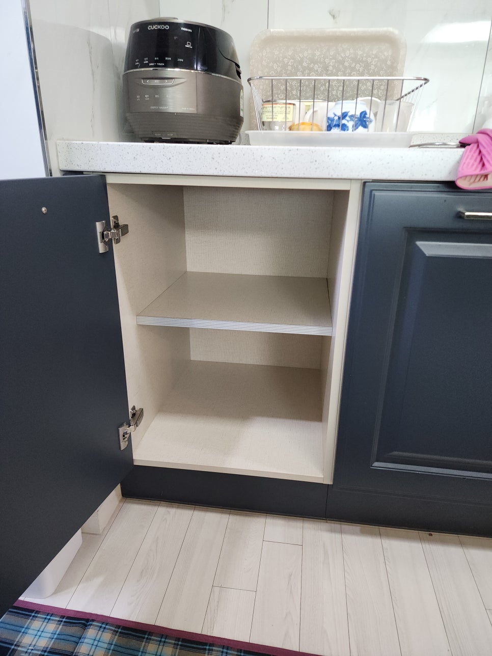 싱크대 왼쪽 수납장 문을 열어 내부 선반을 확인한 모습