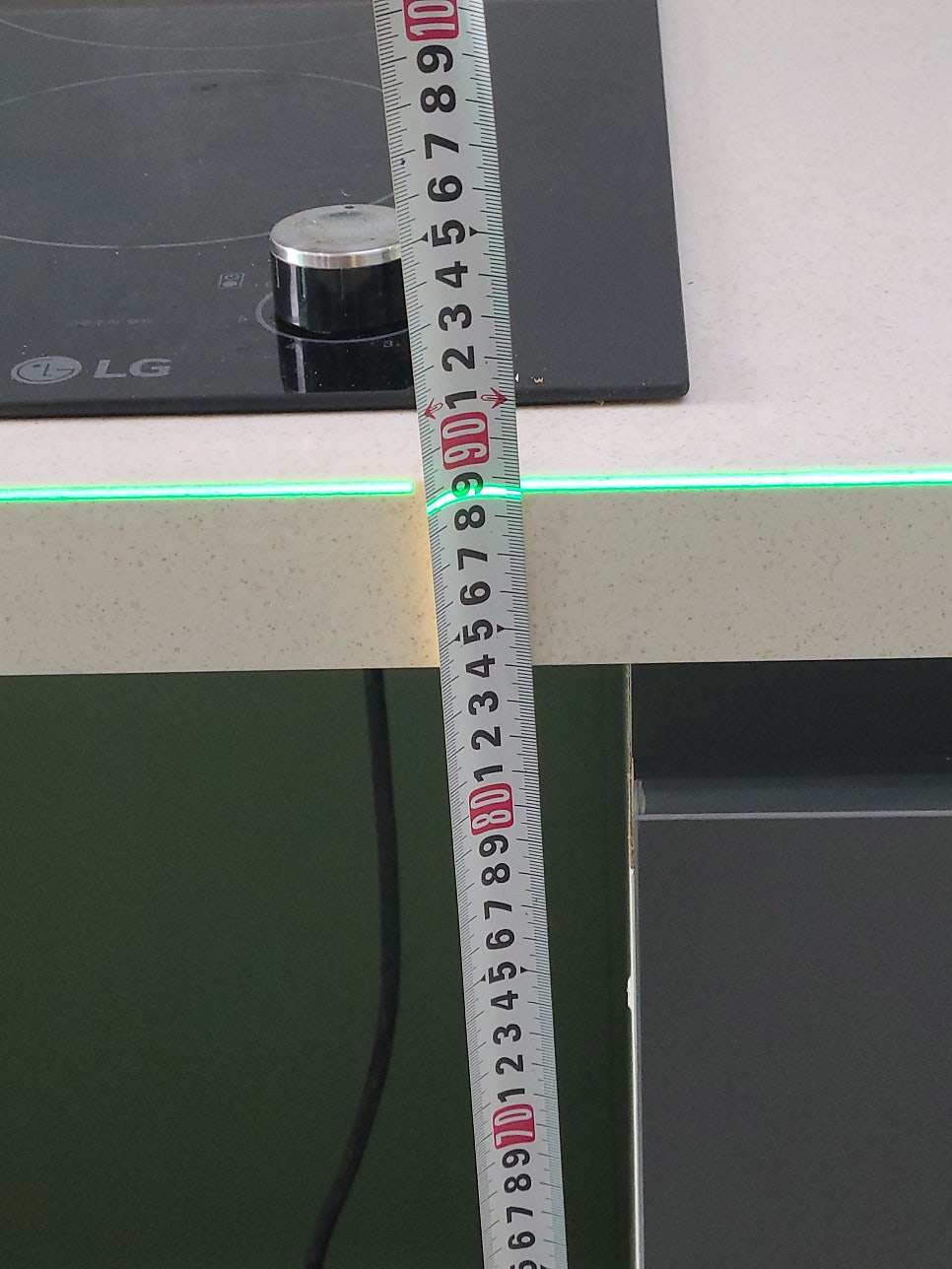 싱크대 상판 앞쪽 높이를 줄자로 다시 확인하는 모습