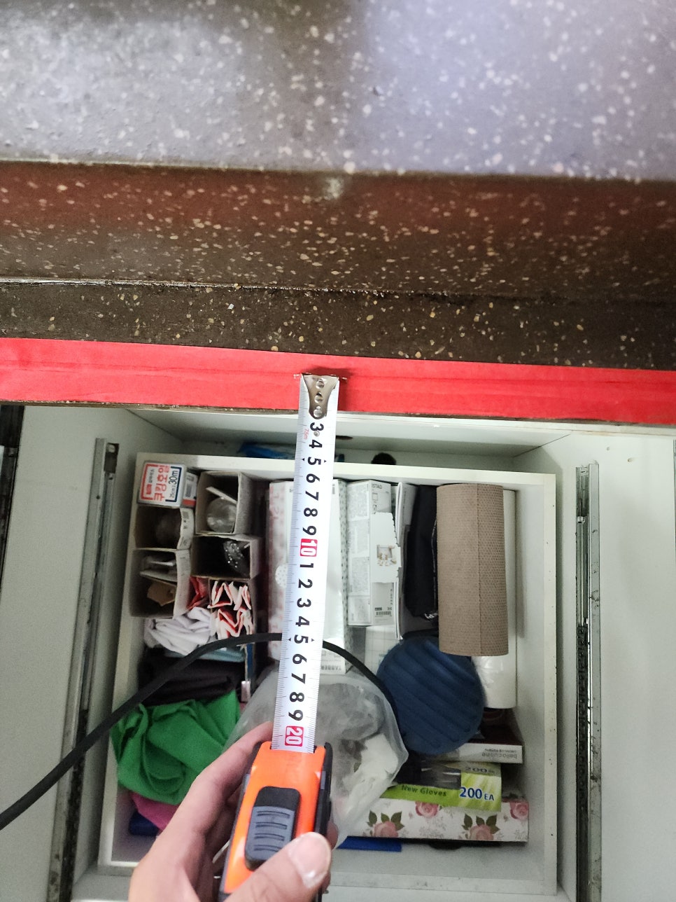 싱크대 상판 아래 공간을 줄자로 재는 모습