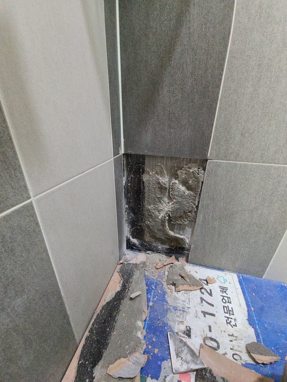 벽면 타일 한 장을 철거해 바탕면이 드러난 샤워 공간