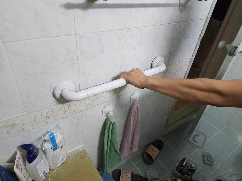 화장실 진입부 벽면 손잡이를 손으로 잡아 고정 상태를 확인하는 모습