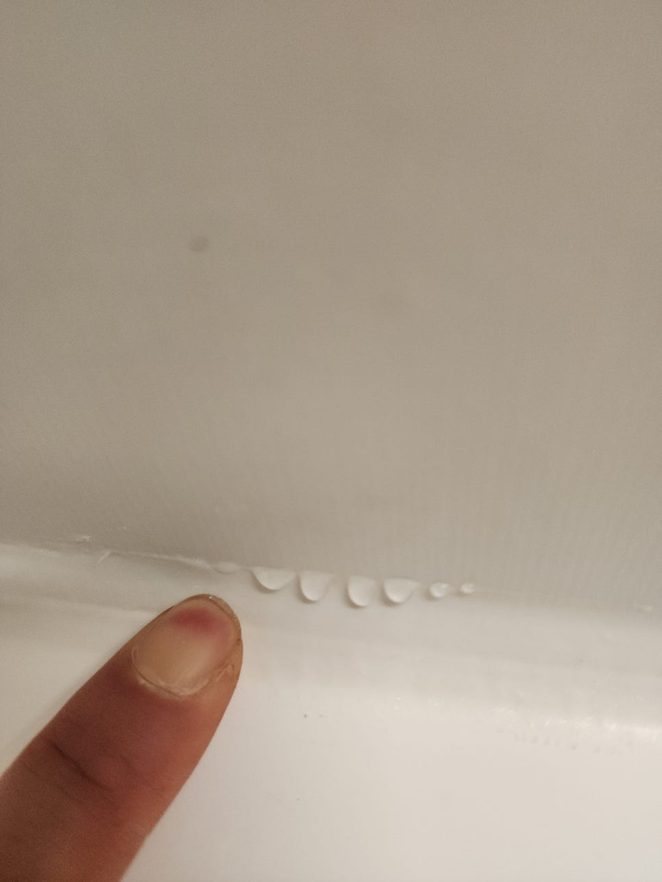 욕조와 벽면 사이 들뜬 테두리를 누르자 맺힌 물방울