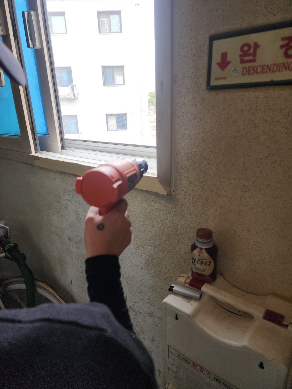 창문틀 하단에서 전동 공구를 사용하는 작업 모습