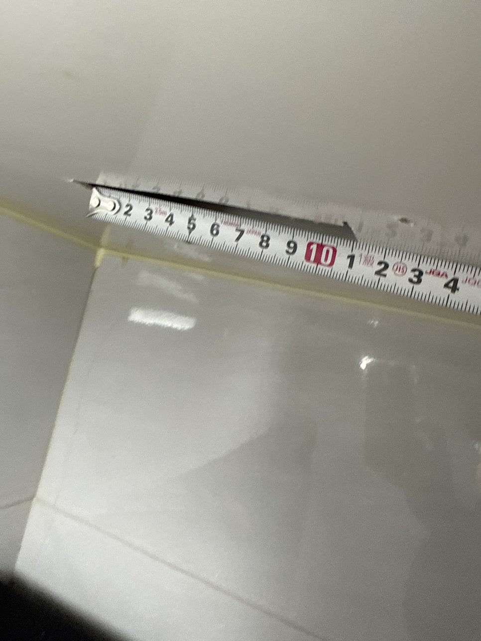 욕실 천장 기존 타공 부위에 줄자를 대고 크기를 재는 모습