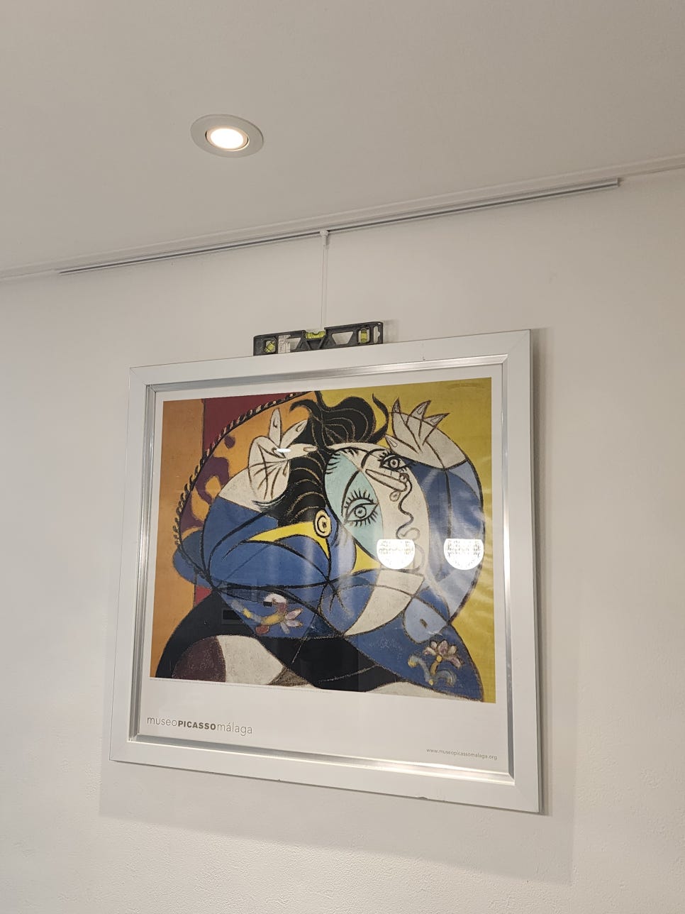 레일 와이어에 건 액자 상단에 수평계를 올려 확인하는 모습