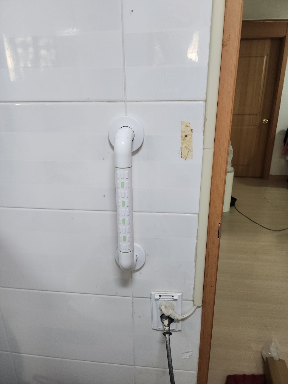 화장실 타일 벽면에 설치한 흰색 세로형 안전바