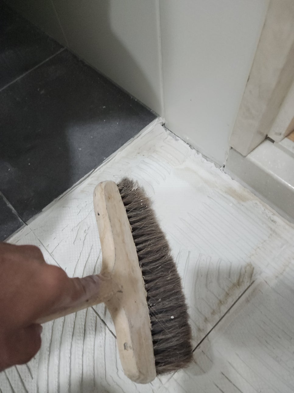 철거한 욕실 바닥면의 잔여물을 빗자루로 정리하는 모습