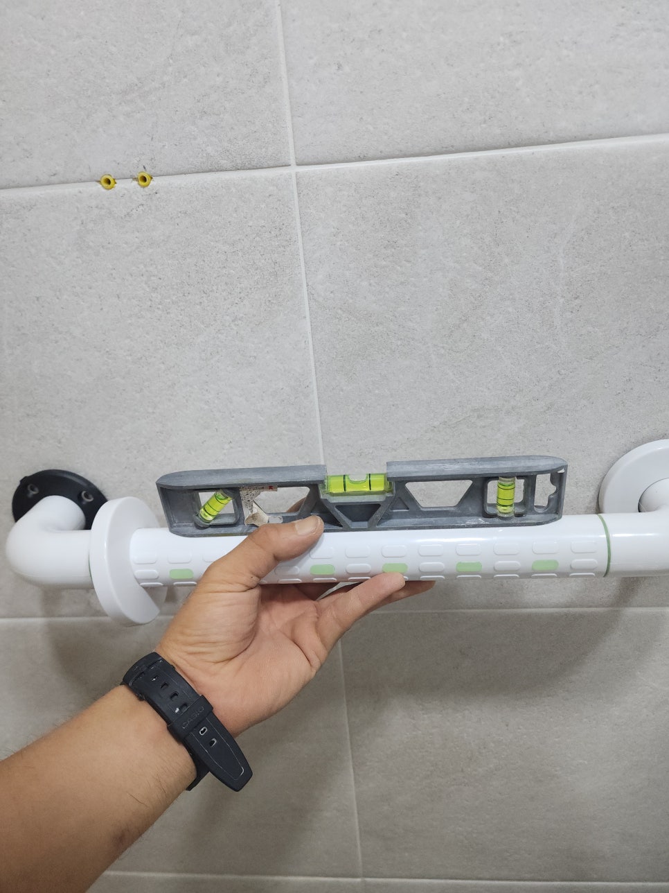 수평자를 대고 타일 벽면의 안전바 위치를 맞추는 모습