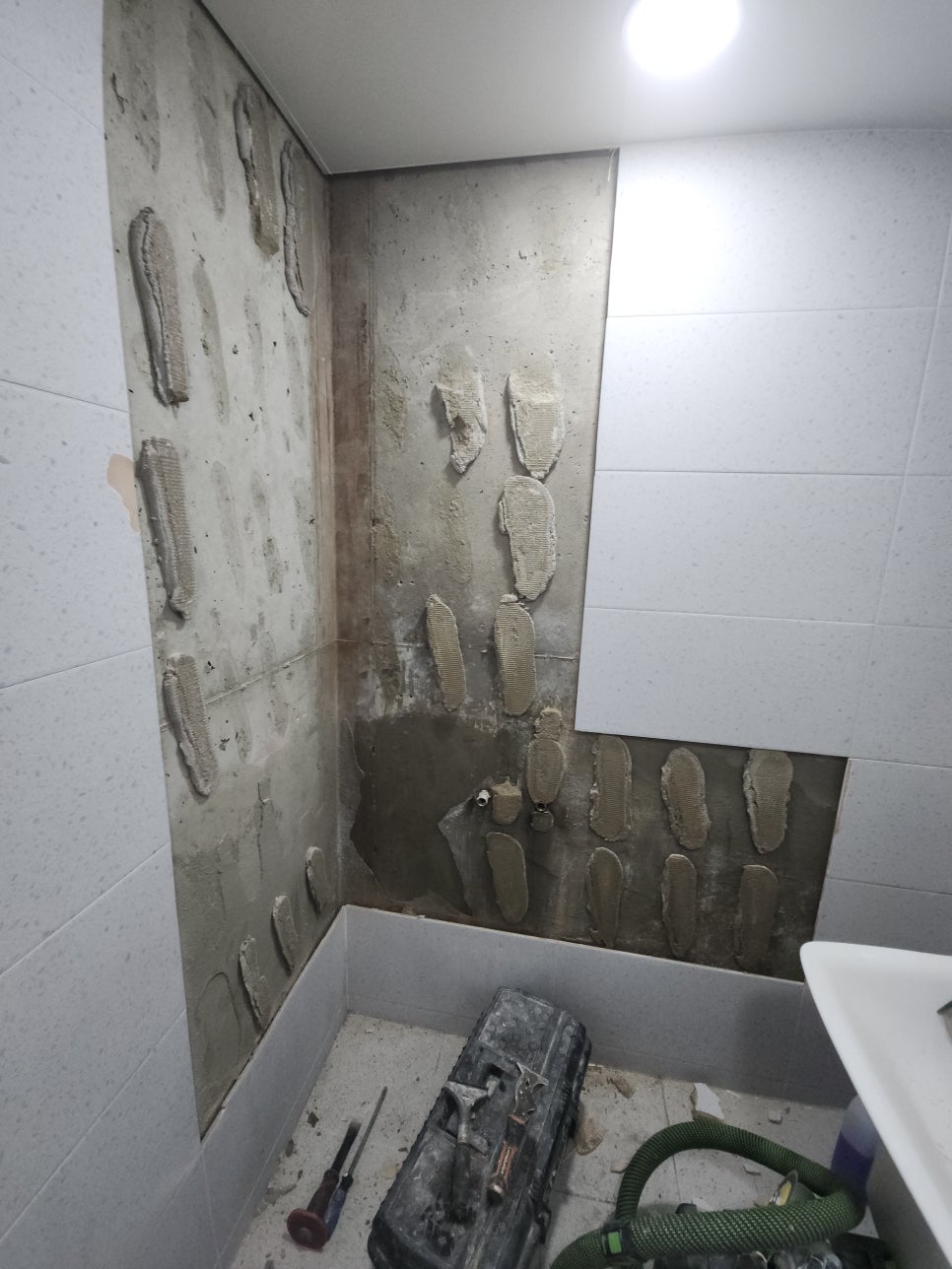 모서리 선반과 수전 거치대를 탈거한 욕실 벽면