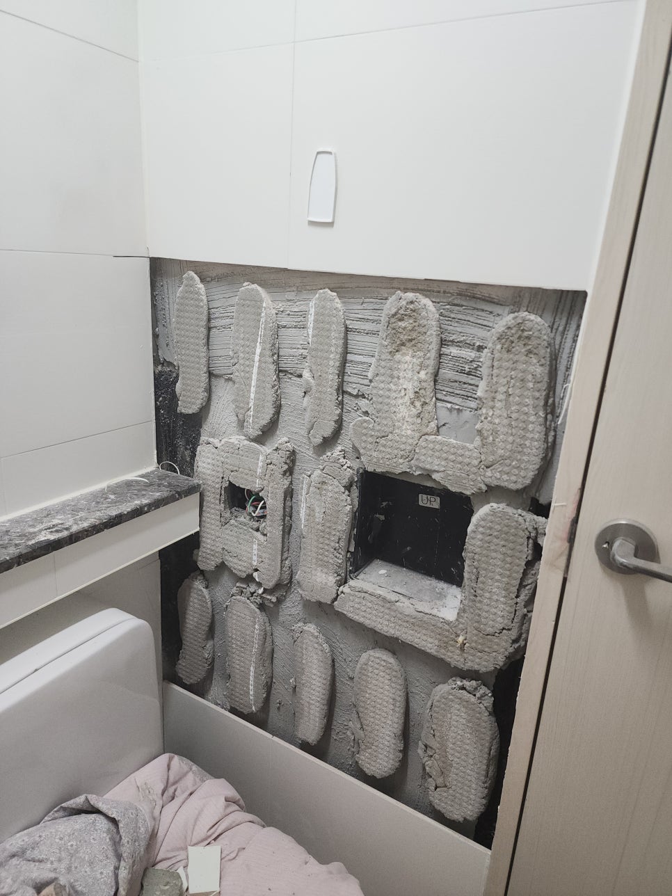 철거한 벽타일 뒷면에 접착 재료가 남은 욕실 벽면
