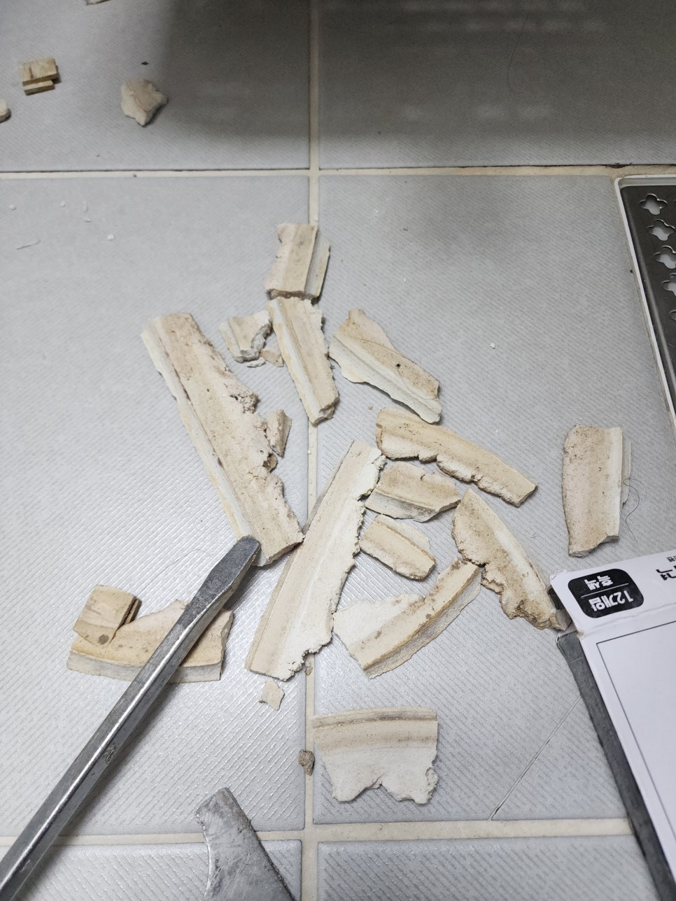 바닥에 모인 제거한 백시멘트 조각과 작업 공구