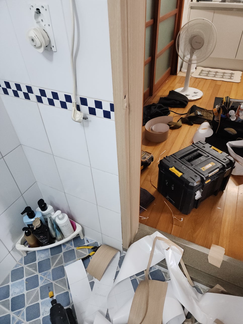 문틀 주변에 필름 자재와 공구를 놓고 마감하는 모습
