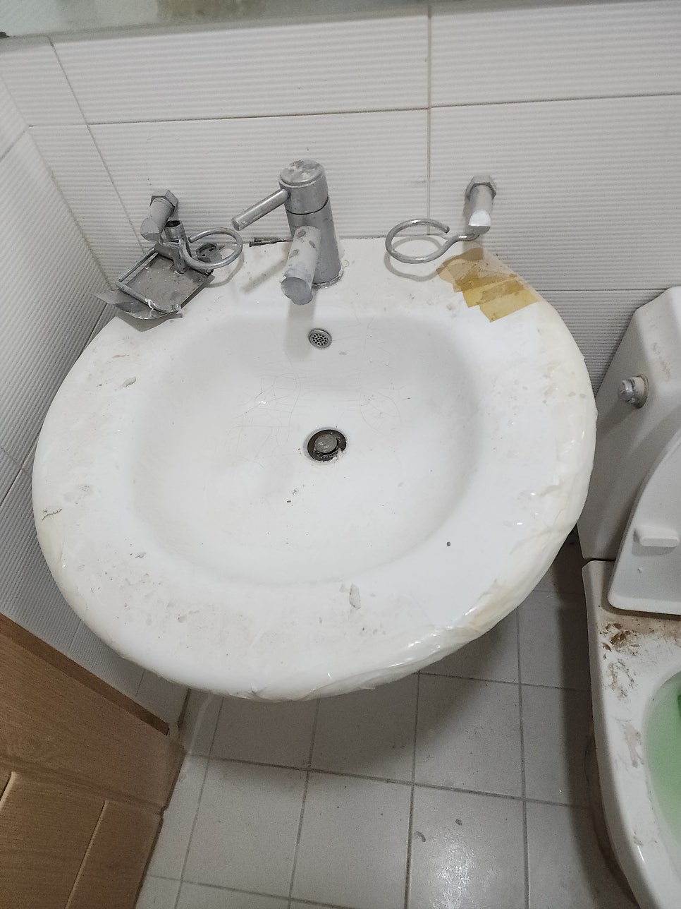 균열과 임시 보수 흔적이 남아 있는 기존 세면대