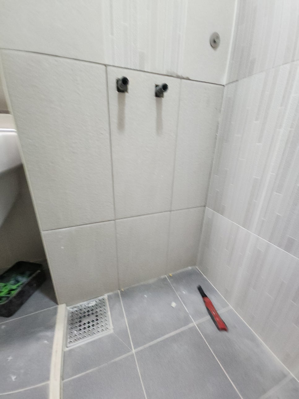 레이저 수평선과 간격재로 새 벽타일을 붙이는 모습