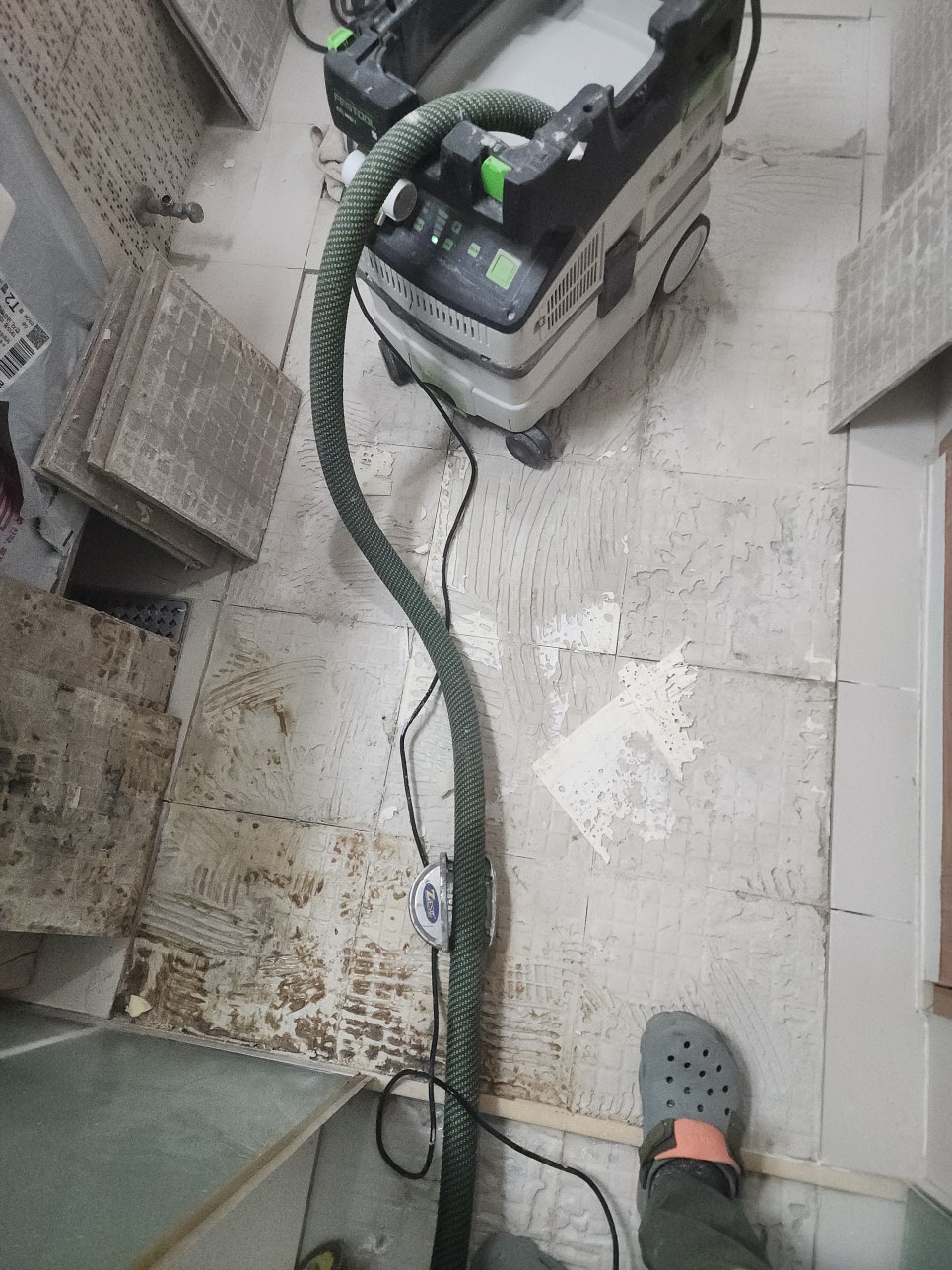 변기 분리 뒤 배수구가 드러난 욕실 바닥과 철거 작업 장비