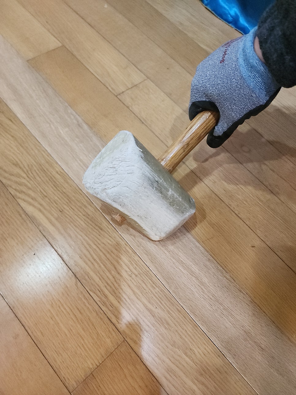 새 마루 판재를 고무망치로 두드려 고정하는 모습