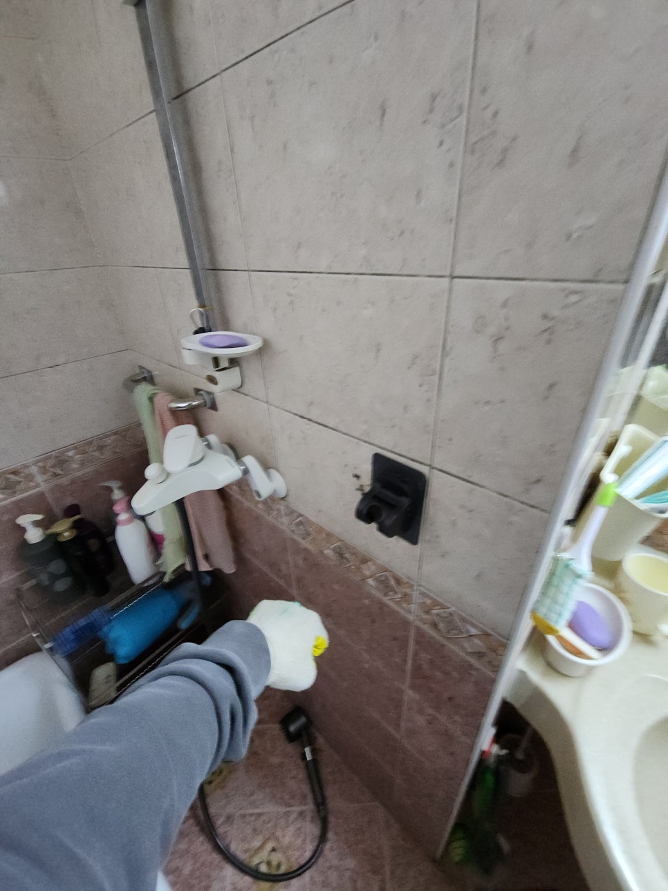 욕실 타일 벽면의 설치 위치를 가리키는 손
