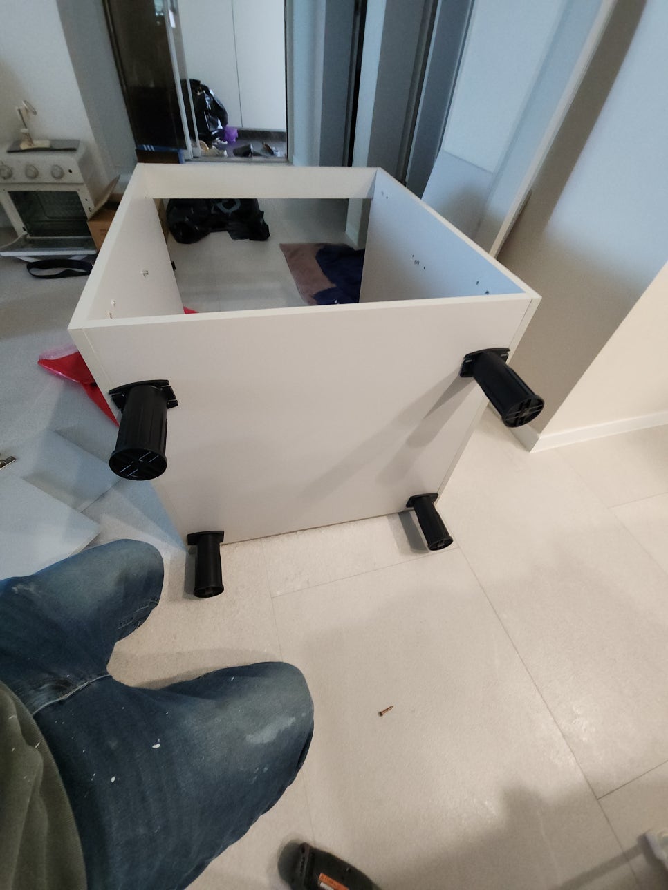 바닥에 눕힌 하부장 몸통에 조절 다리를 설치한 모습
