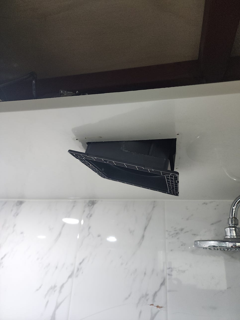 천장 타공부에 설치 중인 검은색 환풍기 본체