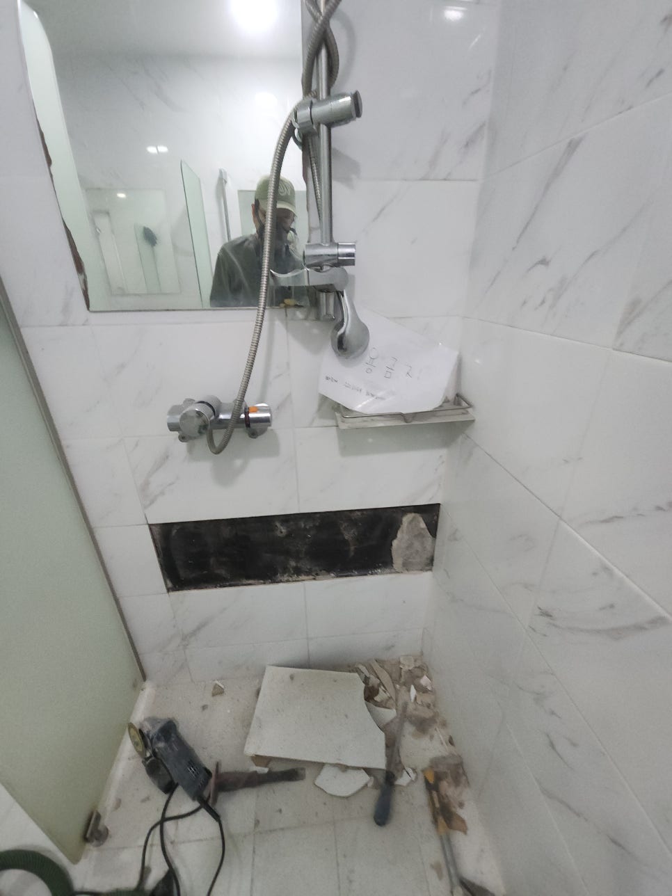 샤워실 벽면에서 파손된 타일 두 장을 철거한 자리